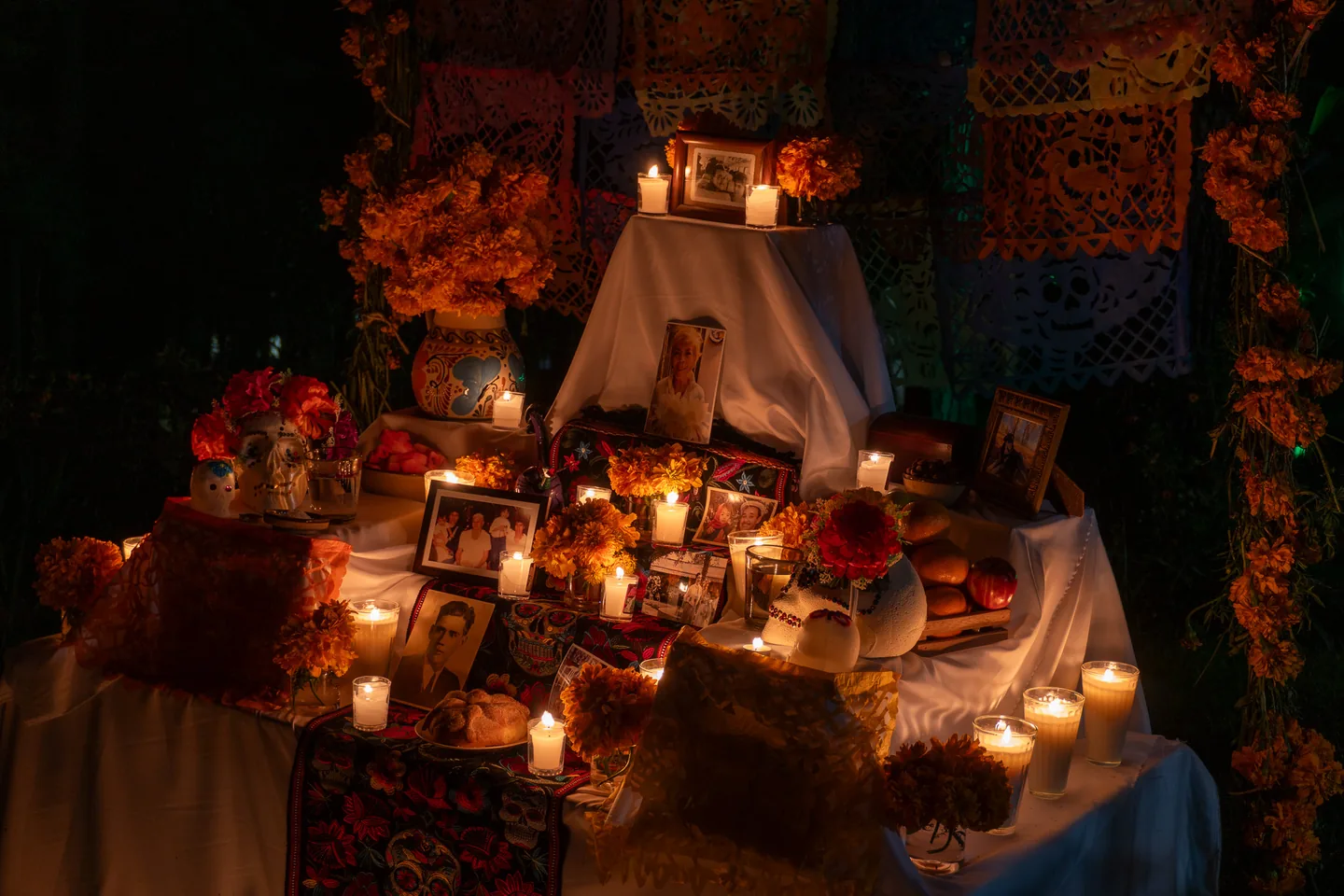 Altar de Día de Muertos con velas encendidas, retratos, cempasúchil y papel picado